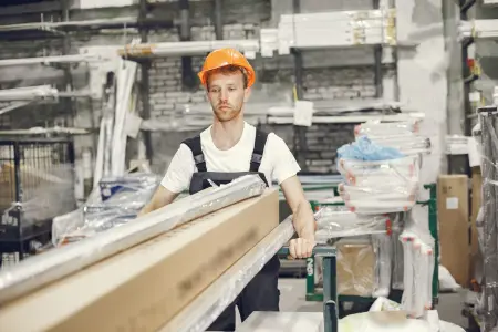 Ein junger Techniker mit orangefarbenem Schutzhelm arbeitet in einer Fabrik.